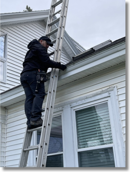 Guardian Home Services inspector on ladder performing roofline inspection in Maine